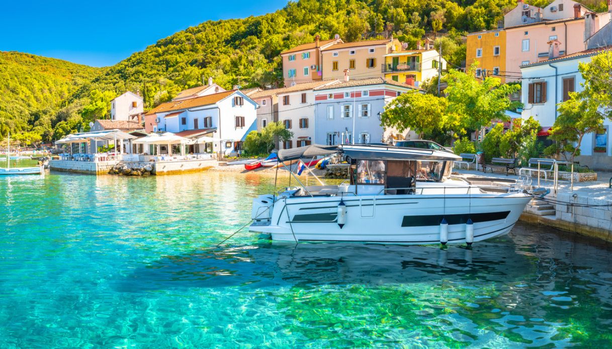 Piccolo porto sull'isola di Cres, con case tradizioni e piccole imbarcazioni su acqua cristallina