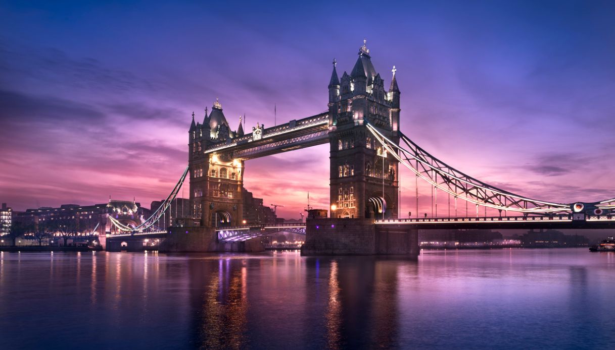 Vista del Tower Bridge dalle sponde del Tamigi al tramonto, con luci accese
